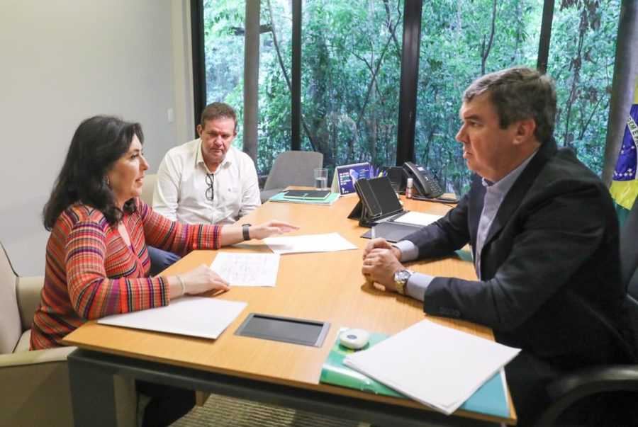 Governador ao lado da ministra Simone Tebet e do secretário da Casa Civil, Eduardo Rocha - Imagem: Saul Schramm Com foco no crescimento do Estado e melhores condições de infraestrutura, o governador Eduardo Riedel discutiu nesta segunda-feira (18) investimentos e obras federais que estão em andamento no Mato Grosso do Sul com a ministra do Planejamento e Orçamento, Simone Tebet.  A reunião ocorreu no Gabinete do Receptivo do Governo do Estado. Entre as obras de infraestrutura em pauta está o acesso à ponte sobre o Rio Paraguai, em Porto Murtinho. A nova alça é essencial para viabilizar o projeto da rota bioceânica e assim encurtar o caminho de Mato Grosso do Sul para o Oceano Pacífico.  A obra que já foi iniciada está sendo feita pelo Governo Federal, tem o investimento de R$ 472,4 milhões. Lá será pavimentado um trecho de 13 km ligando a BR-267 até o local onde está sendo construída a ponte binacional, entre Porto Murtinho e Carmelo Peralta. Além da alça, está previsto a construção de um centro aduaneiro e um trabalho de terraplanagem, para um acesso elevado à ponte.  Também foi discutido o contorno rodoviário em Três Lagoas, assim como a restauração de estradas e rodovias federais dentro do Mato Grosso do Sul. Outro assunto de destaque é a concessão das rodovias que fazem parte da “Rota da Celulose”, que vão a leilão no próximo dia 6 de dezembro. Neste pacote estão trechos da BR-262 (Campo Grande a Três Lagoas) e BR-267 (Bataguassu a Nova Alvorada do Sul) que foram cedidos pela União ao Estado.